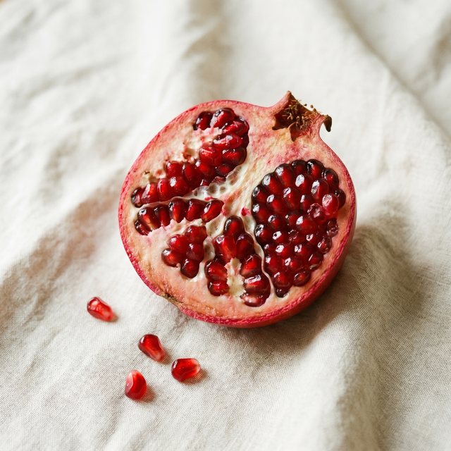 A pomegranate split open to reveal glistening ruby-red seeds.
